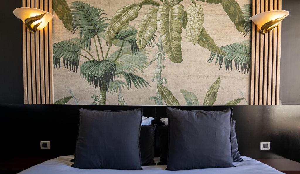 戛纳Hôtel Gallia Cannes的一张带两个枕头的床和一幅画墙