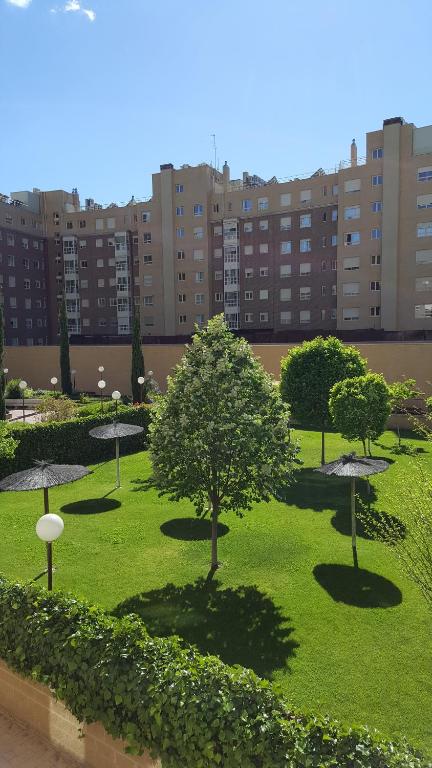马德里Madrid Las Tablas apartments的一座有树木和草的公园,其背后是建筑