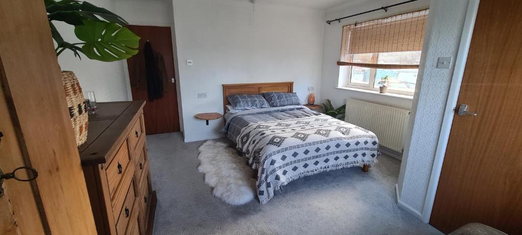 纽基The Cornish Getaway的一间卧室配有一张带床罩的床和窗户