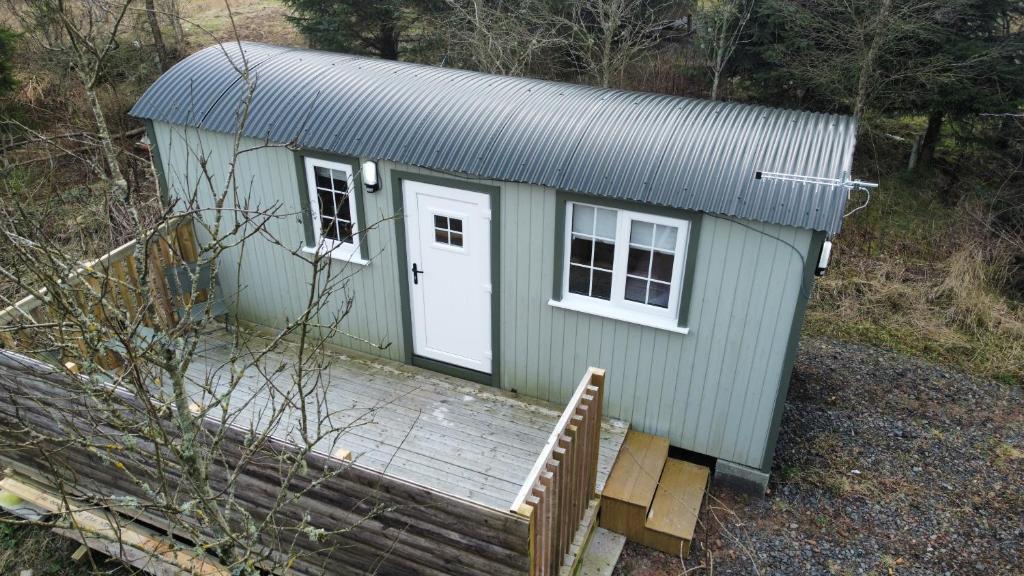 KeltyBlair snug hut的绿色的小房子,设有门廊和白色的门