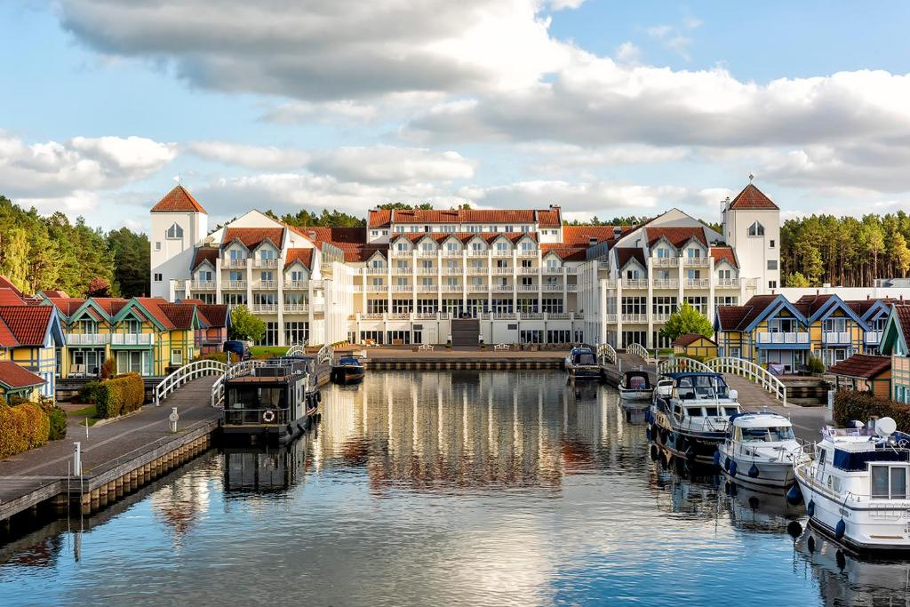 赖因斯贝格Precise Resort Hafendorf Rheinsberg的河里有船的城市,有建筑物