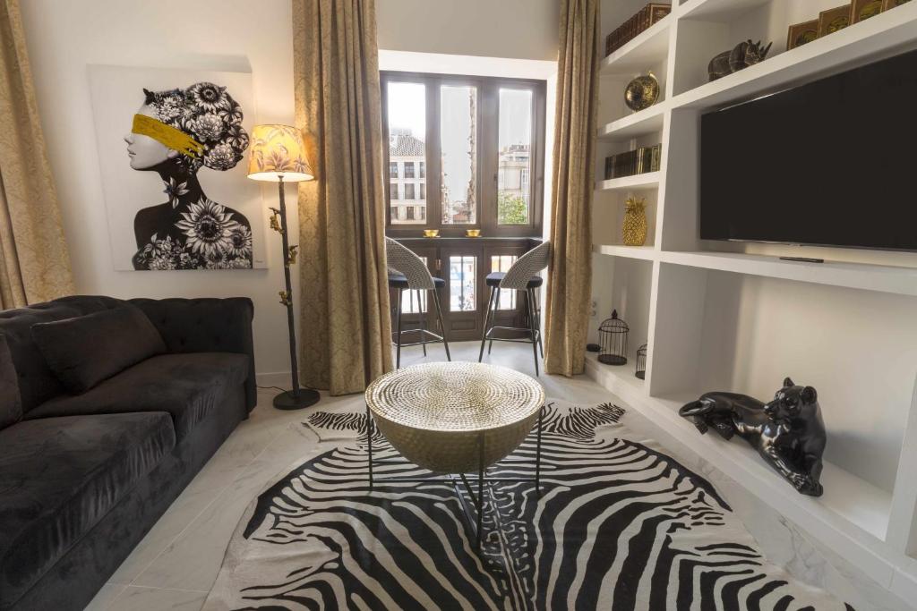 马拉加THE CLOCK HOUSE Luxury Urban Suites的一间设有斑马地毯和电视的客厅
