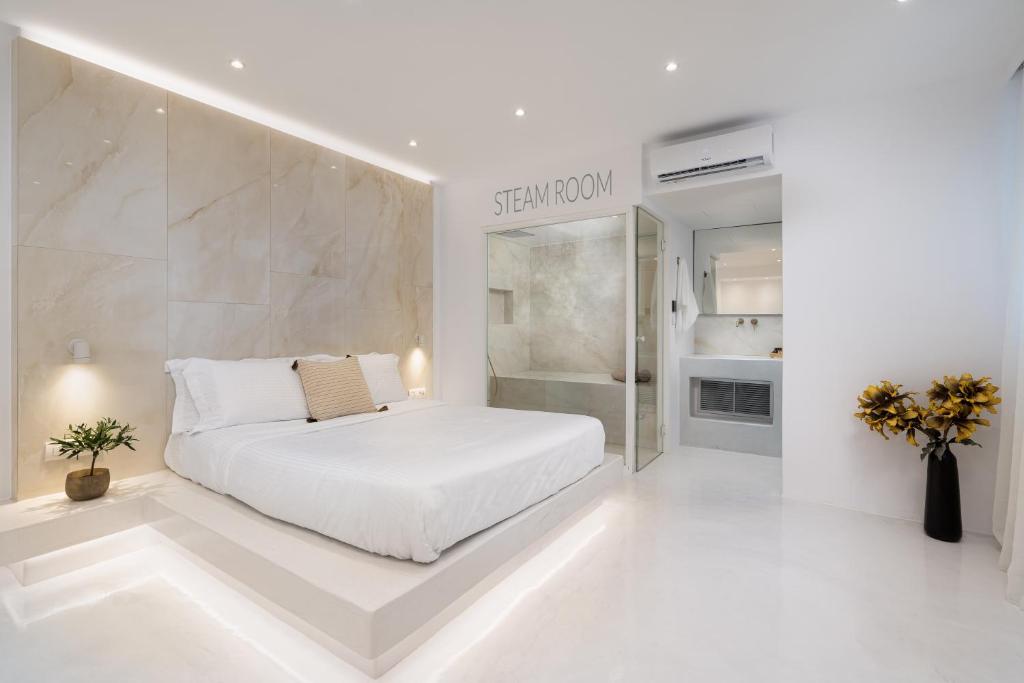 费拉Cycladic Suites的白色卧室设有一张床和一个步入式淋浴间