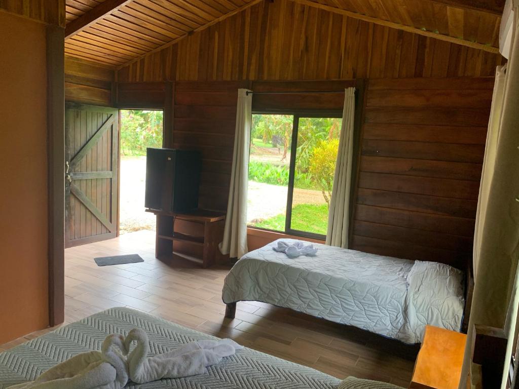 比加瓜Cataratas Bijagua Lodge, incluye tour autoguiado Bijagua Waterfalls Hike的一间卧室配有两张床和一台平面电视