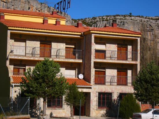 Vega del CadornoHotel Restaurante Rio Cuervo的一座带红色屋顶的大建筑,山中