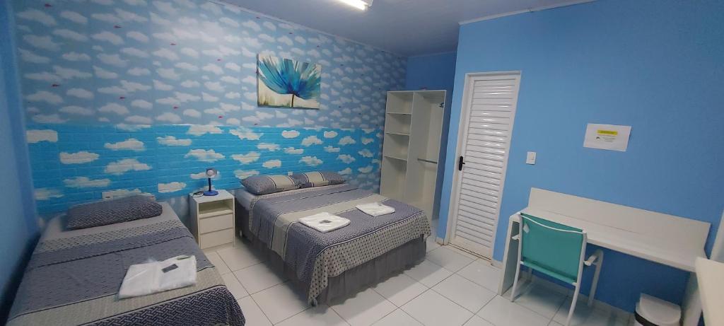 马瑙斯Hotel Colors Manaus的一间卧室设有两张床和蓝色的墙壁
