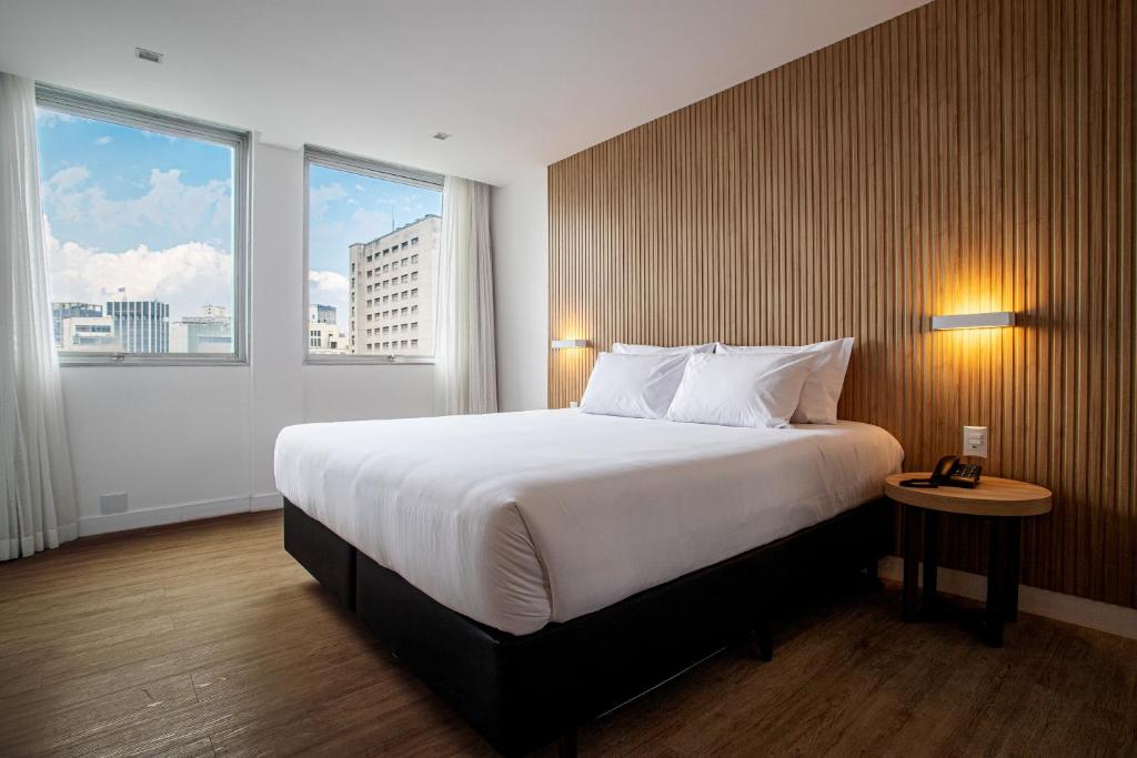 圣保罗Sooz Hotel Collection的酒店客房设有一张大床和两个窗户。