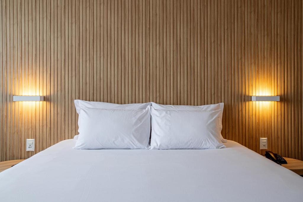 圣保罗Sooz Hotel Collection的一间卧室配有带2个枕头和2盏灯的床
