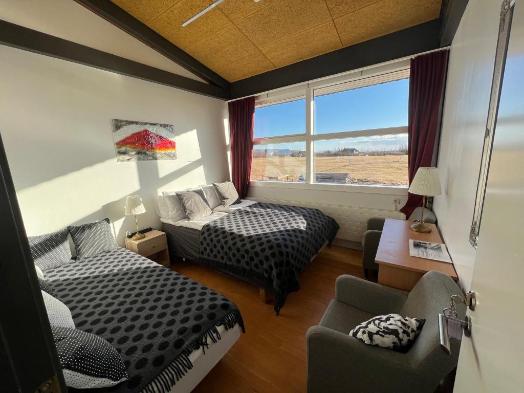 HlíðarendiGodaland Guesthouse and Glamping的客房设有两张床、一张沙发和一个窗口。