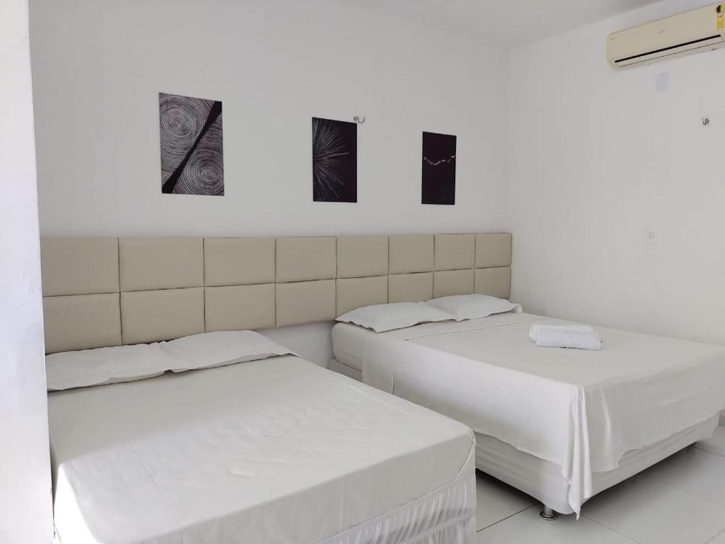 圣阿马鲁Ville Portal das Dunas Suites - St Amaro的墙上有三张照片的房间的两张床
