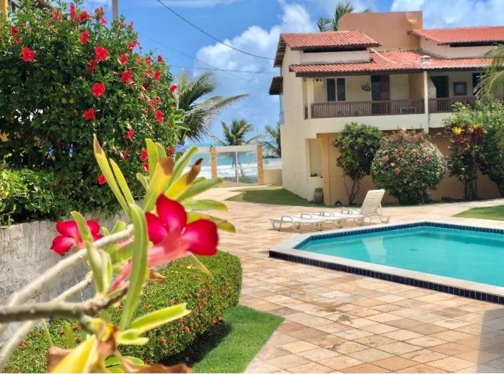 尼西亚弗洛雷斯塔Duplex Beira-mar em condomínio / Búzios-RN的院子中带游泳池和花的房子