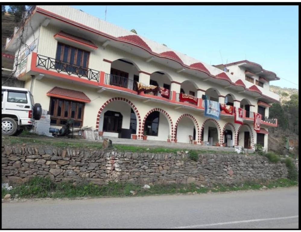 乌德尔格希Hotel Krish Motel and Restaurant, Uttarkashi的前面有石墙的大建筑