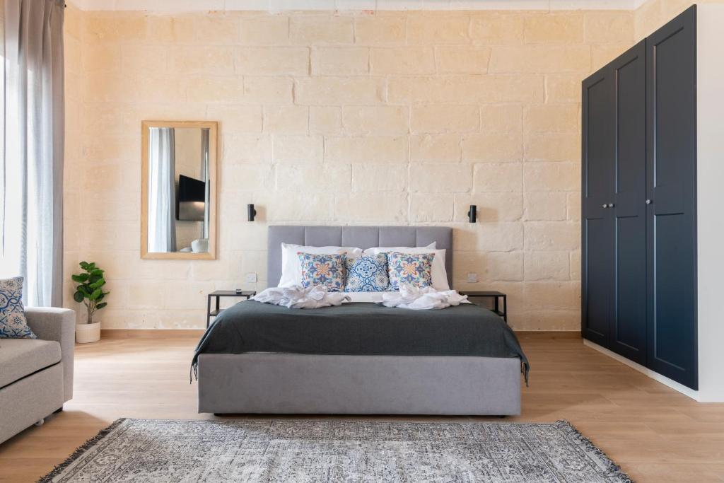 瓦莱塔Valletta Collection - Felix Apartments的一间卧室配有一张床、一张沙发和一面墙