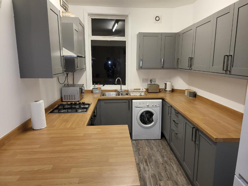 奇德尔Cheadle village的厨房配有灰色橱柜、洗衣机和烘干机