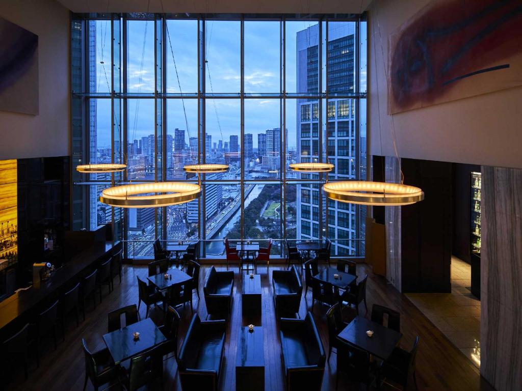 东京The Royal Park Hotel Iconic Tokyo Shiodome的餐厅设有桌椅和大窗户。