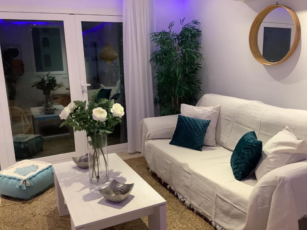 普拉亚登博萨Apartamento Playa Denbossa的客厅配有白色的沙发和带鲜花的桌子