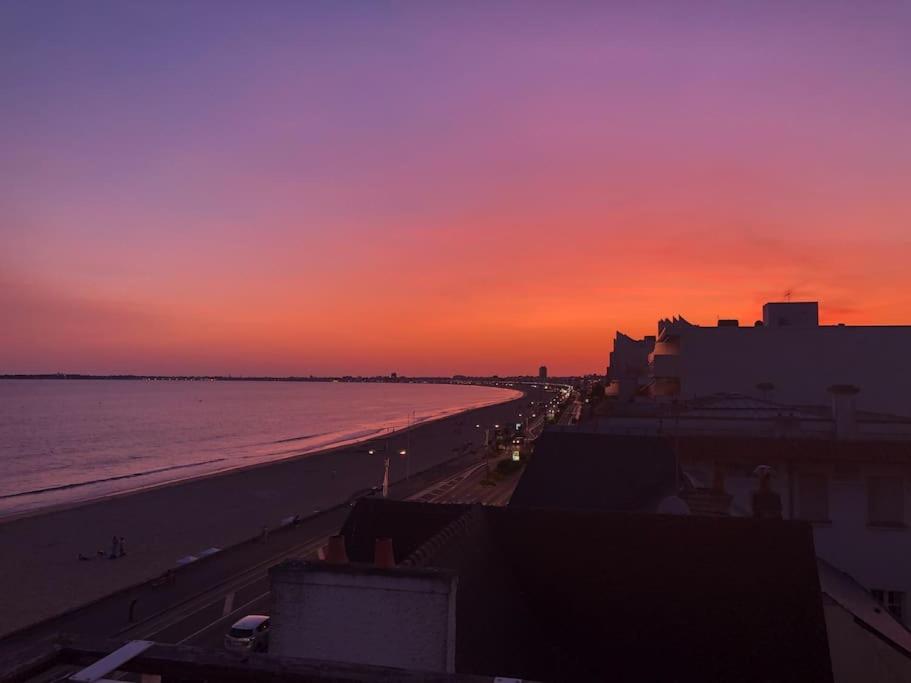 波尔尼谢Magnifique Penthouse Pornichet的海滩上的日落与海洋和建筑