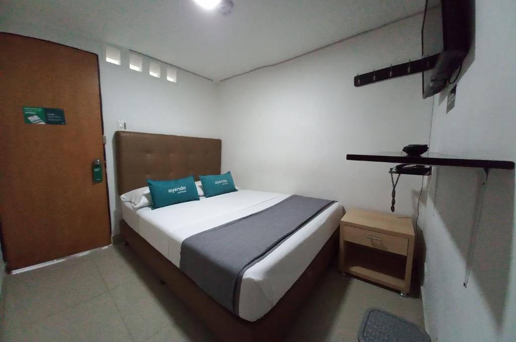 麦德林Ayenda Colombia Avenida的一间卧室配有一张带两个蓝色枕头的床