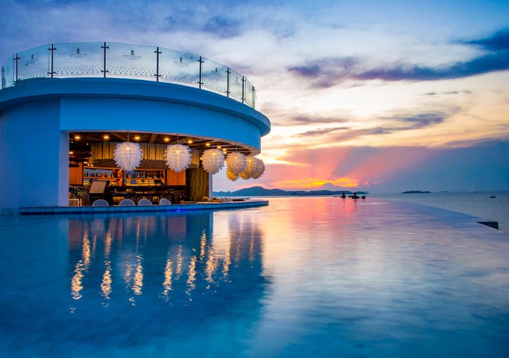 南芭堤雅Royal Cliff Beach Terrace Pattaya的水面上的建筑,背景是日落