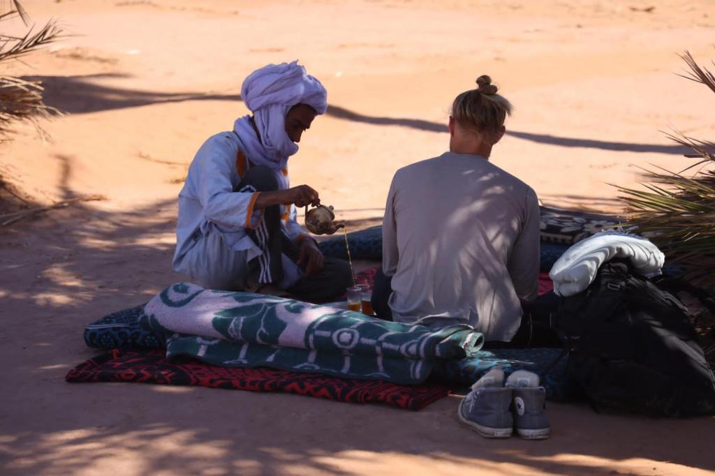 MhamidBivouac Beauté de Désert的两个人坐在地上的毯子上