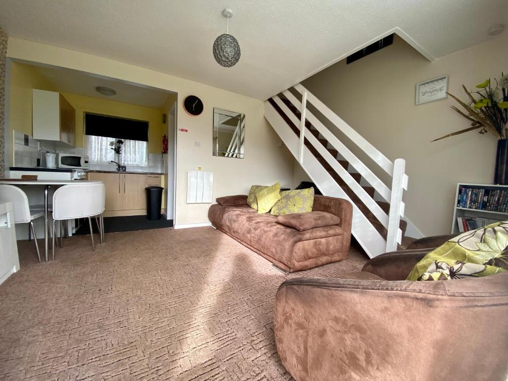 大雅茅斯Cosy and Comfortable Holiday Chalet 10 minutes walk to the beach, Norfolk的客厅设有两张沙发和一个楼梯