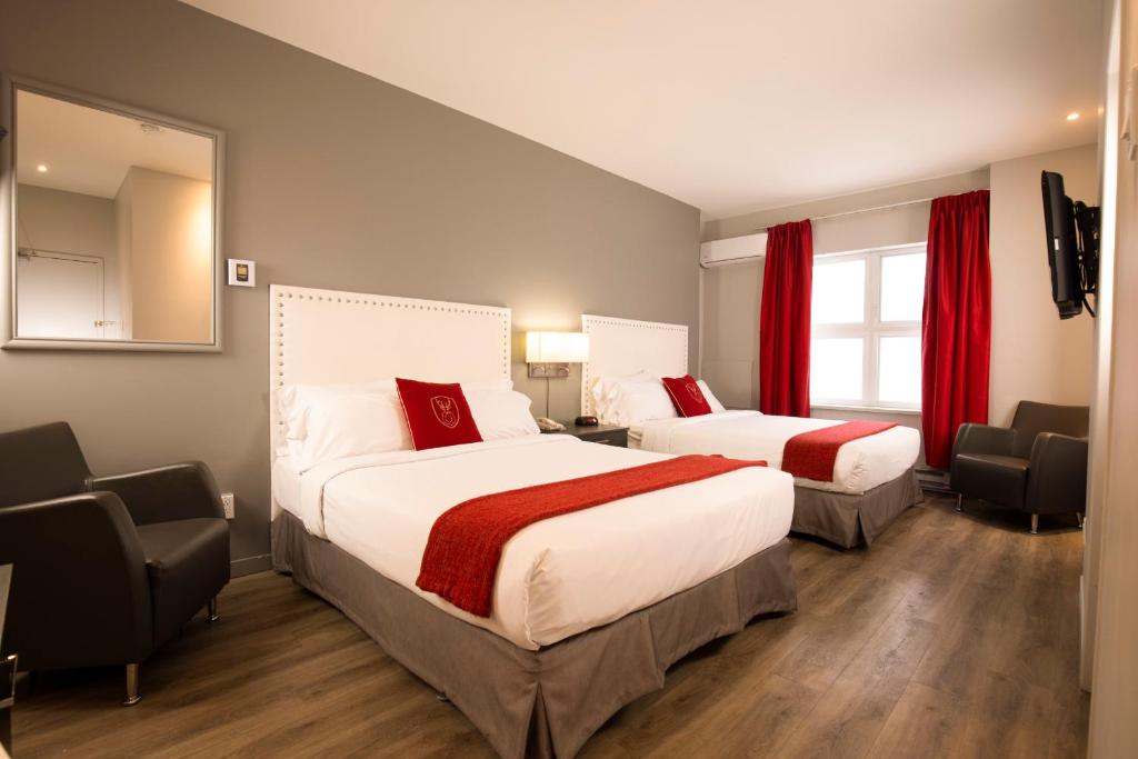 魁北克市北方酒店的配有红色窗帘的酒店客房的两张床