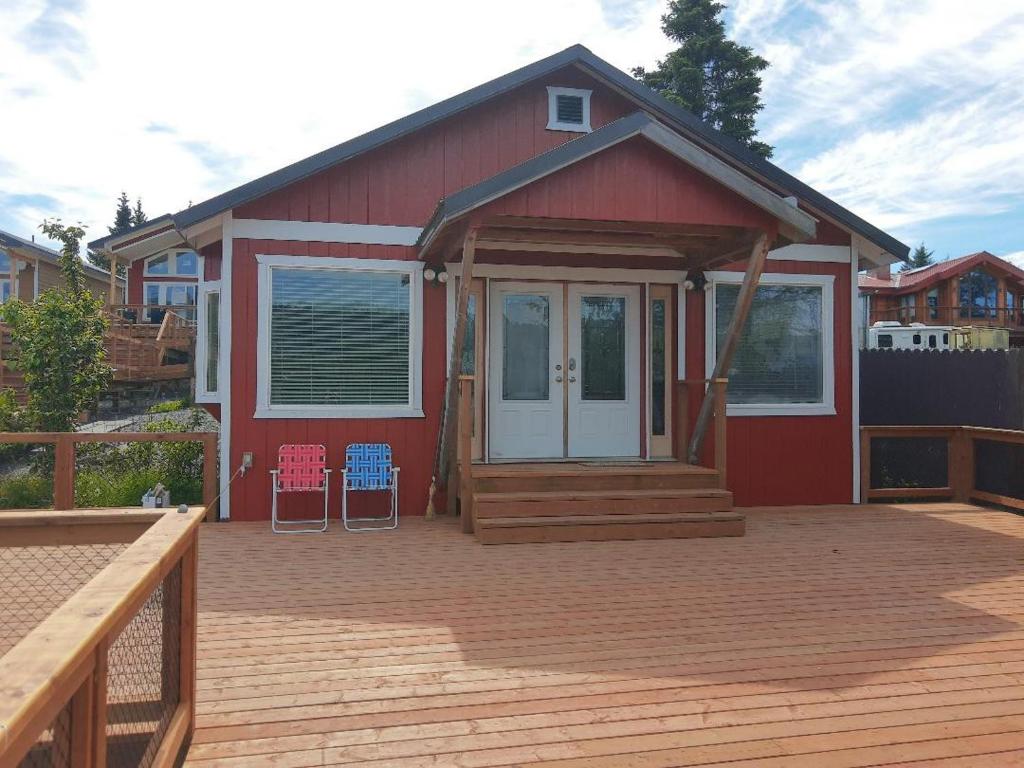 荷马Waterfront Cabin - Homer Seaplane Base的红色的房子,配有带两把椅子的甲板