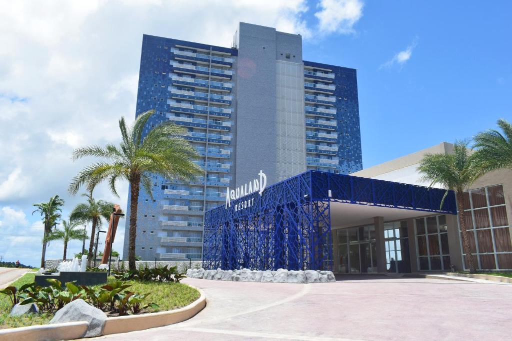 萨利诺波利斯Aqualand Park & Resort Oficial的酒店建筑拥有蓝色的外观和棕榈树