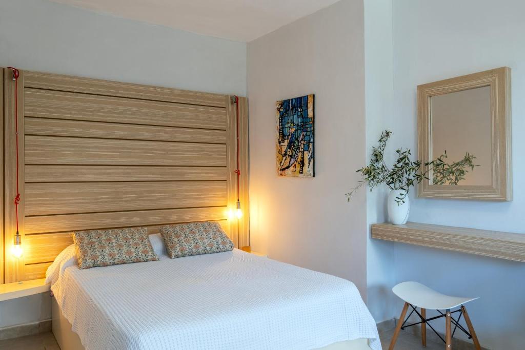 干尼亚Coco Studio的卧室配有白色的床和木制床头板