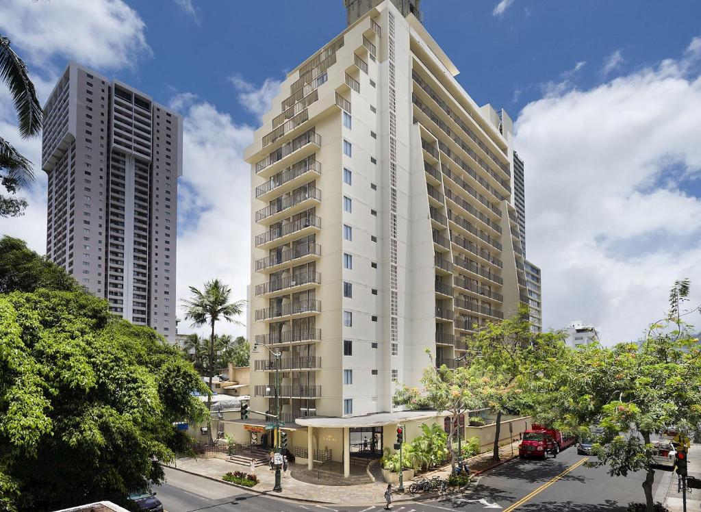 檀香山Ohia Waikiki Studio Suites的一座高大的白色建筑,两座高大的建筑