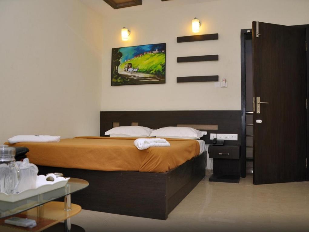 库姆巴科纳姆Hotel Metro的一间卧室配有一张床,一扇门通往一个房间