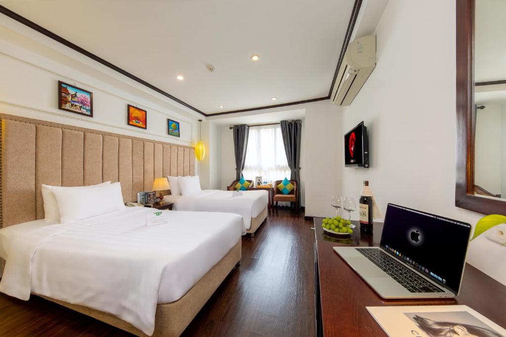 河内Babylon Grand Hotel & Spa的酒店客房配有两张床和一张带笔记本电脑的书桌