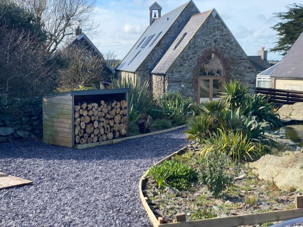 阿姆奇Converted chapel - Sant Pedr Newydd - with sea views的教堂前花园,花园内堆满了木柴