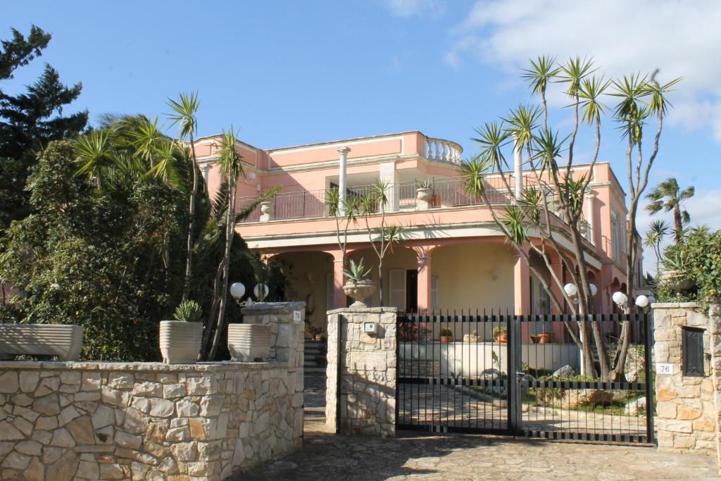 卡斯特里尼亚诺德尔卡波Villa la Bifora by Salento com的一座粉红色的房子,设有大门和棕榈树