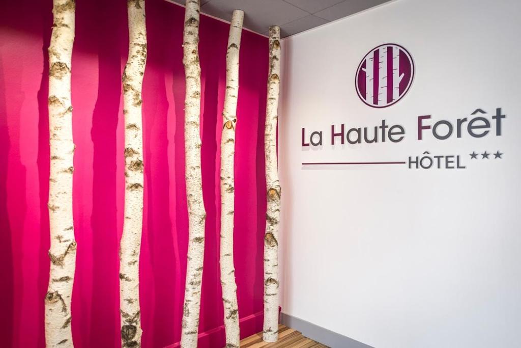 韦尔图Logis hôtel restaurant la Haute Forêt的一间设有粉红色窗帘和酒店标志的客房