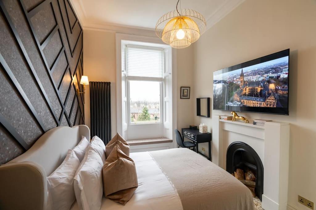 格拉斯哥The Devonshire Suite - Your 5 STAR West End Stay!的一间卧室设有一张床、电视和壁炉