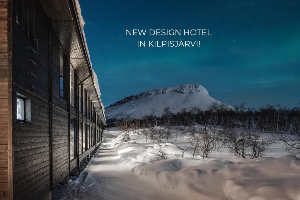 基尔匹斯扎我维Santa's Hotel Rakka的一座有积雪覆盖的山,与一座建筑相隔不远