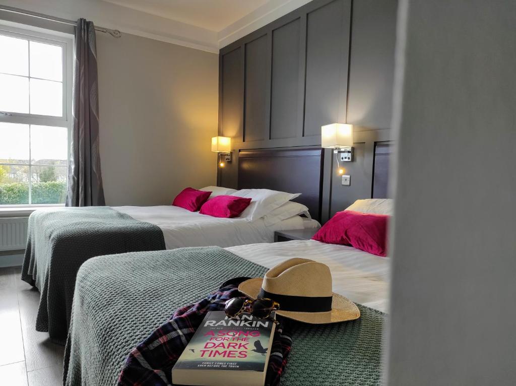 基尔肯尼Kilkenny House Boutique Hotel的酒店客房,设有两张床,地板上有一顶帽子