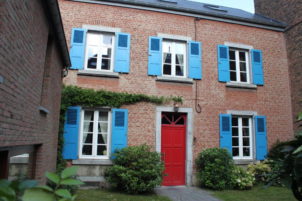 那慕尔Chambre d'hôte Les Volets Bleus的红砖建筑,有蓝色百叶窗和红色门