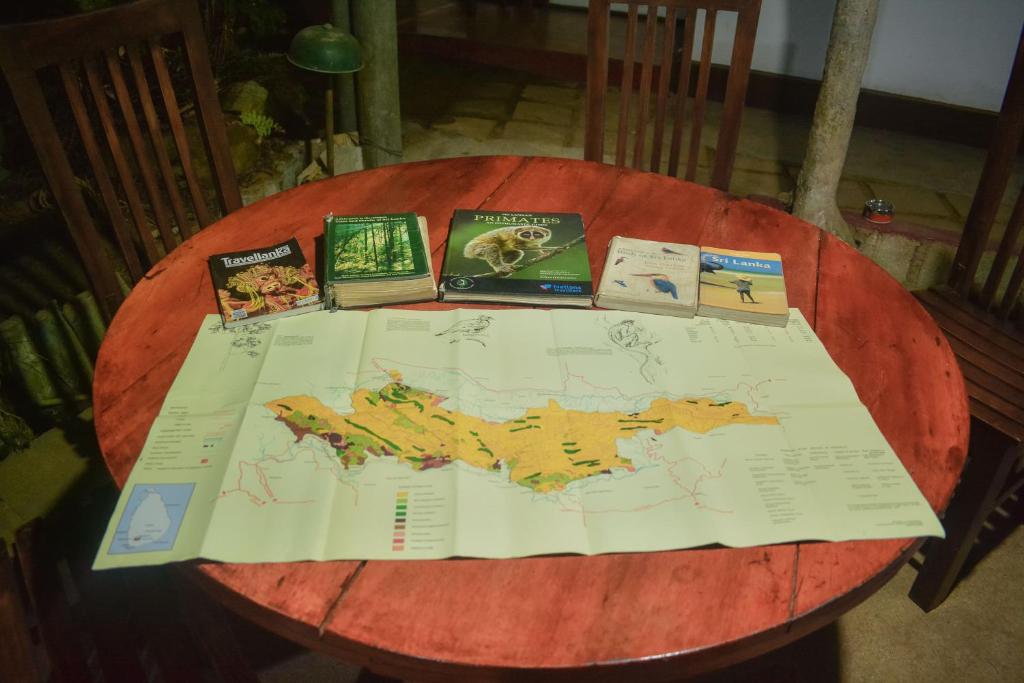 代尼耶耶Sinharaja Tour Hostel的一张木桌,上面有地图和书籍
