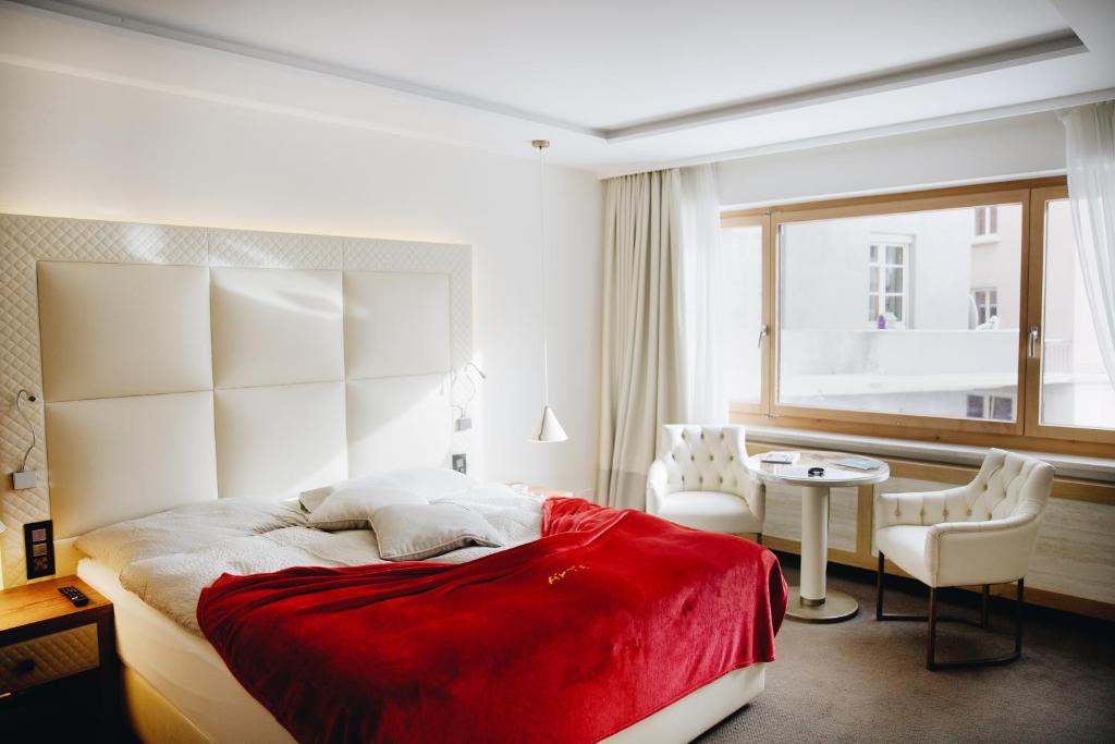 圣莫里茨阿尔特酒店的一间卧室配有一张床、一张桌子和一个窗户。