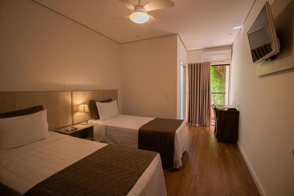 安帕鲁Prado Hotel的酒店客房设有两张床和电视。