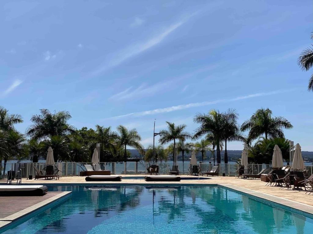 巴西利亚Harmonia à Beira do Lago - Life Resort的一个带椅子和遮阳伞的游泳池以及棕榈树