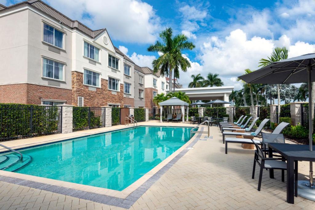 萨拉索塔Courtyard by Marriott Sarasota at University Town Center的一座带桌椅的游泳池位于酒店大楼旁