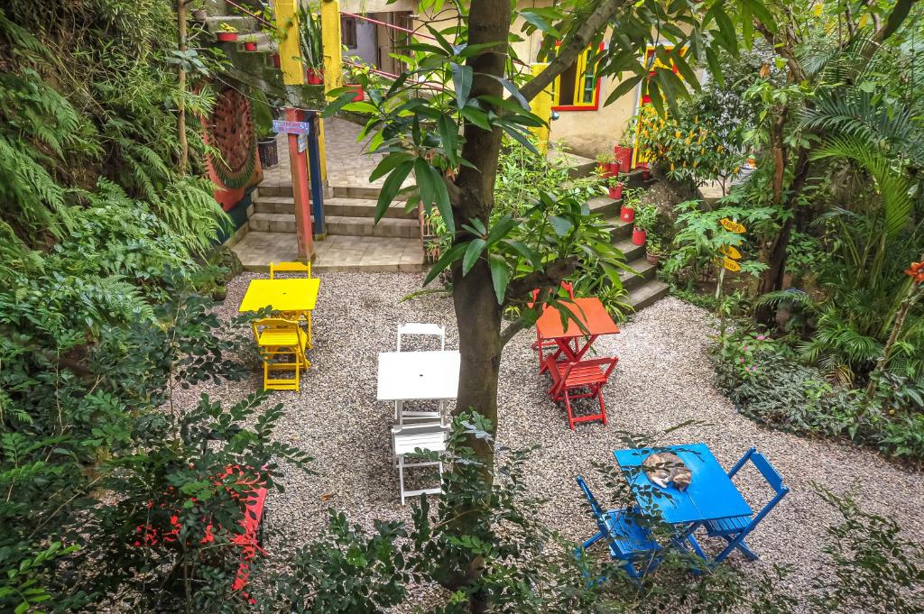 里约热内卢Eco Pousada Estrelas da Babilônia的花园,花园内摆放着五颜六色的椅子和一棵树