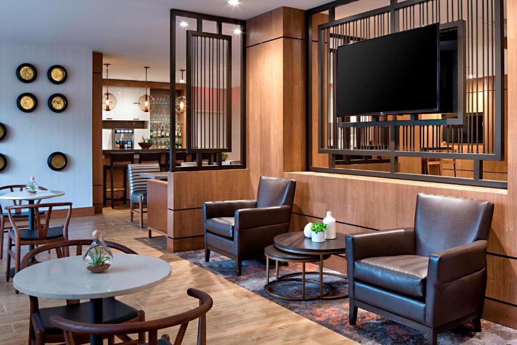 休斯顿休斯敦万豪韦斯特彻斯酒店的一间设有桌椅和平面电视的等候室