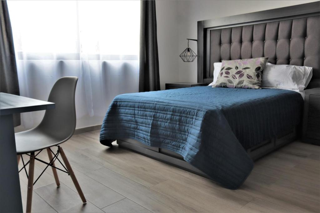 瓜达拉哈拉Expo Satelite Hotel & Suites的一间卧室配有一张床、一张桌子和一把椅子