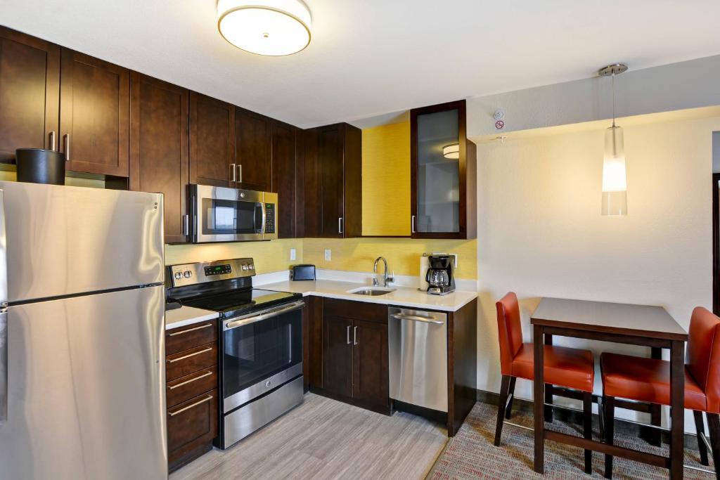 GlendaleResidence Inn by Marriott Milwaukee North/Glendale的厨房配有木制橱柜和不锈钢冰箱。