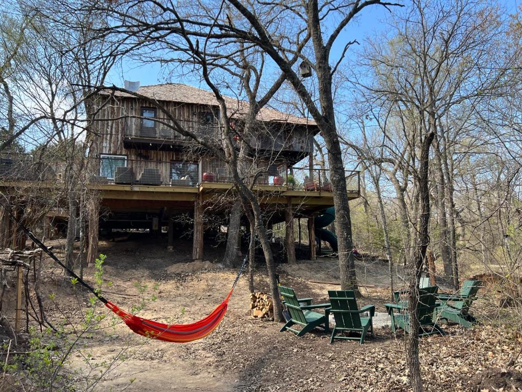 韦瑟福德"Magical Treehouse" w spiral slide off the deck 350 acres on the Brazos River! Tubing! Petting Zoo!的树林中房子前面的吊床