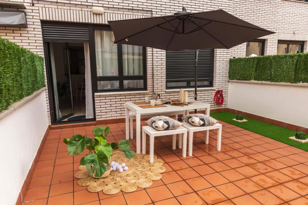 奥维多LA TERRAZA DE LA VEGA - Ubicación inmejorable , wifi , terraza y parking gratuito的一个带桌子和遮阳伞的庭院